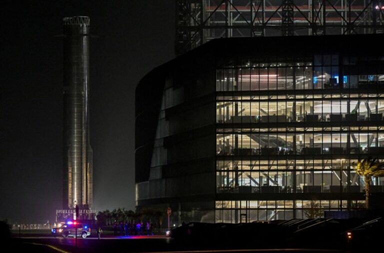 The SpaceX Super Heavy booster rolls past the production facility toward the launchpad ahead of the 12th test flight of the Starship spacecraft in Starbase, Texas, on May 18.