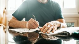 cropped image of senior men writing crossword on newspaper