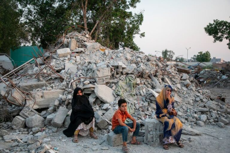 Two women and a child sit in ruins at Al-Shajara Al-Tayyiba School on May 13, 2026, in Tehran, Iran.