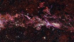 This image shows the complex distribution of molecular gas in the Central Molecular Zone (CMZ) of the Milky Way. It was obtained with the Atacama Large Millimeter/submillimeter Array (ALMA), in which ESO is a partner. This map is as long as three full Moons side-by-side in the sky, and it is in fact the largest ALMA image ever obtained.
This map is part of ACES — the ALMA CMZ Exploration Survey — a project designed to understand how gas condenses into stars in the extreme and chaotic environment at the heart of our galaxy. The survey has charted the distribution of dozens of different molecules, five of which are shown here in different colours: sulphur monoxide (cyan), silicon monoxide (green), isocyanic acid (red), cyanoacetylene (blue), and carbon monosulphide (magenta).
The stars in the foreground of this image were observed at infrared wavelengths (Y, Z and J filters) with ESO’s VISTA telescope as part of a different project. The actual density of stars in the CMZ is much higher than what is shown here, where we have opted to highlight the details in the molecular cloud. Note that the edges of the ALMA map appear somewhat sharp because the ALMA observations do not cover the entire rectangular area here.