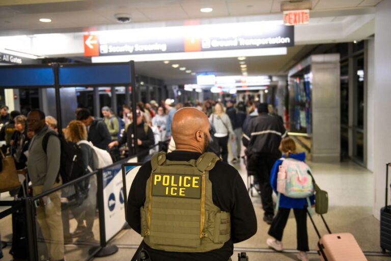 An ICE agent stands alongside a long line of travelers waiting to pass through a TSA checkpoint at the Philadelphia International Airport on March 28.