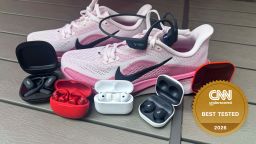 Various running headphones sit next to a pair of Nike running shoes.