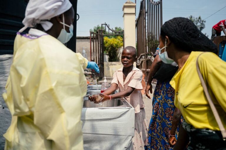A young girl washes her hands at the checkpoint outside Kyeshero Hospital in Goma, DRC.