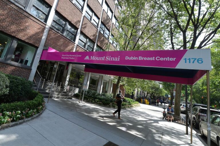 A woman wearing a mask walks under the awning entrance of Mount Sinai Dubin Breast Center on Fifth Avenue in New York, NY on August 21, 2020.