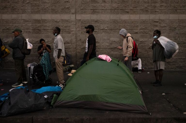 Homeless people wait in line for dinner outside the Midnight Mission in the Skid Row area of Los Angeles, in October 2023.