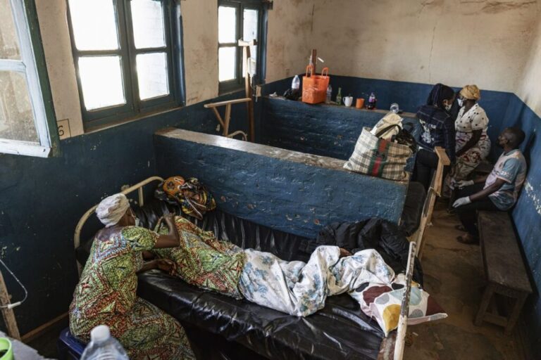 A woman sits beside a relative believed to have died from Ebola at the General Referral Hospital of Mongbwalu in Ituri Province, DRC, on Wednesday.