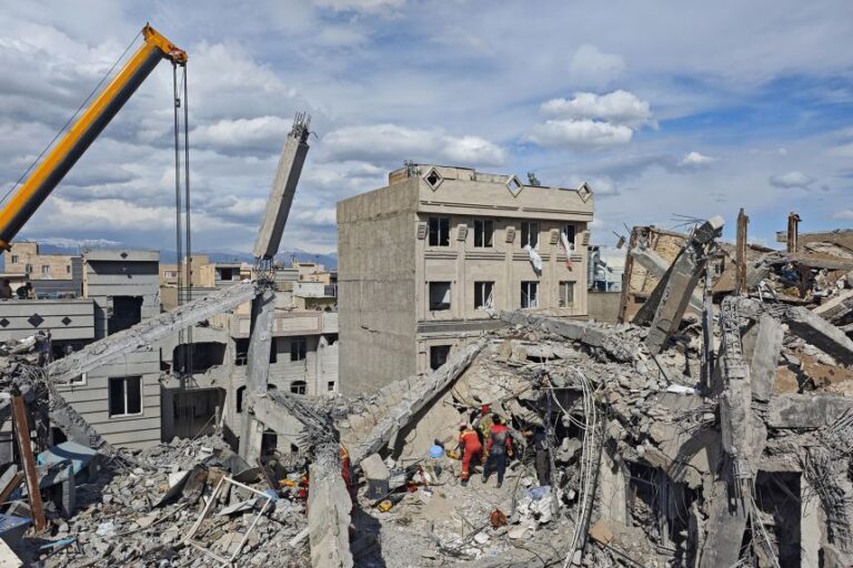 Rescue workers search for bodies in the rubble of a residential building following a hit in an airstrike in the early hours of March 27, in Tehran, Iran.