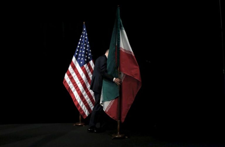 A staff member removes the Iranian flag from a stage during nuclear deal talks in Vienna, Austria, in 2015.