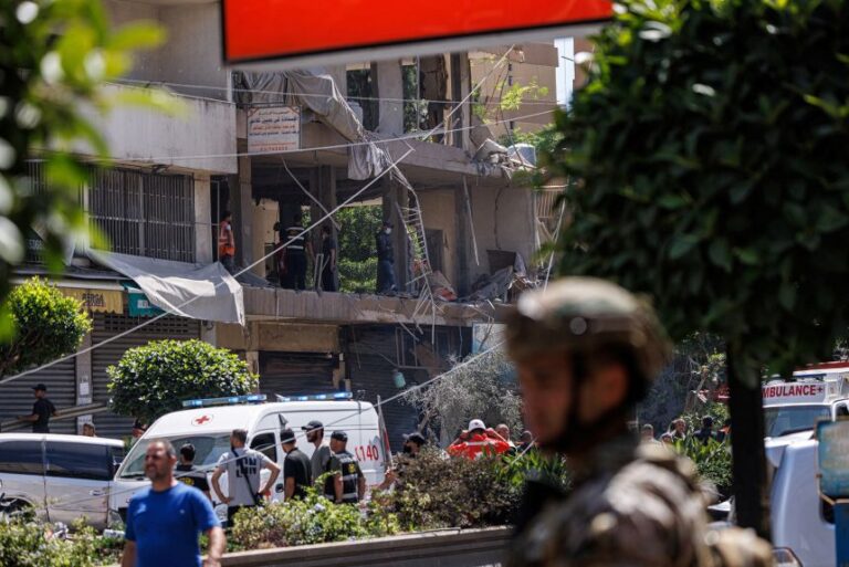 A Lebanese army officer stands as police officers and emergency personnel work at the site of an Israeli strike on the southern suburbs of Beirut, Lebanon, on June 14.