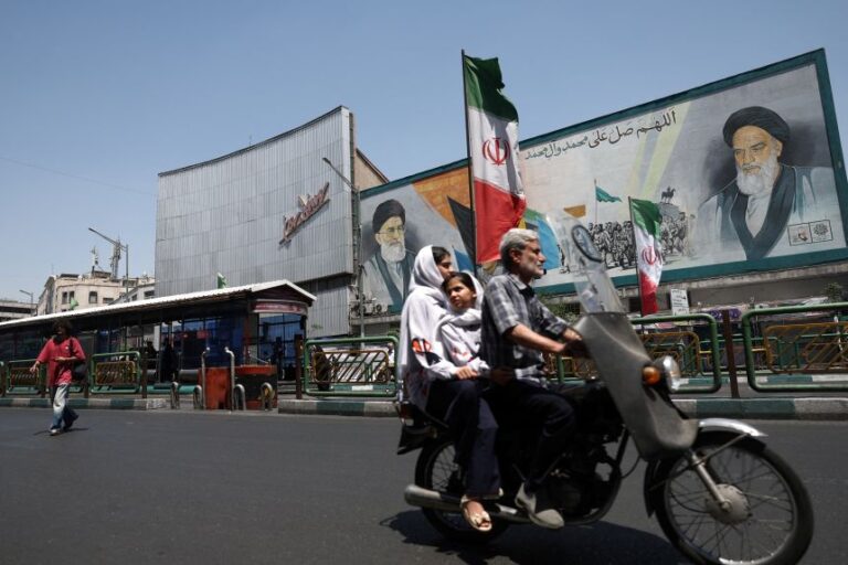 People ride past a mural depicting the late leader of the Islamic Revolution, Ayatollah Ruhollah Khomeini, and Iran's late Supreme Leader Ayatollah Ali Khamenei, on a street in Tehran on June 9, 2026.