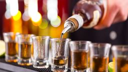 Bartender pouring hard spirit into glasses