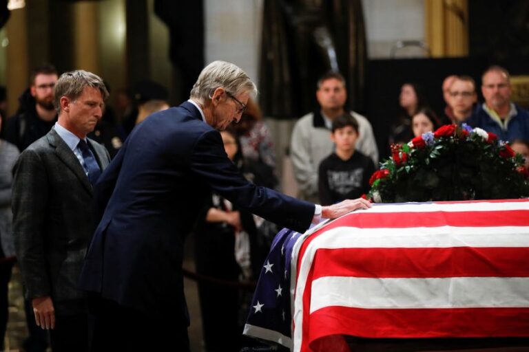 Jonathan Bush watches as his father places his hand on the casket of his uncle, former US President George H.W. Bush as he lies in state inside the US Capitol Rotunda on Capitol Hill, on December 4, 2018.