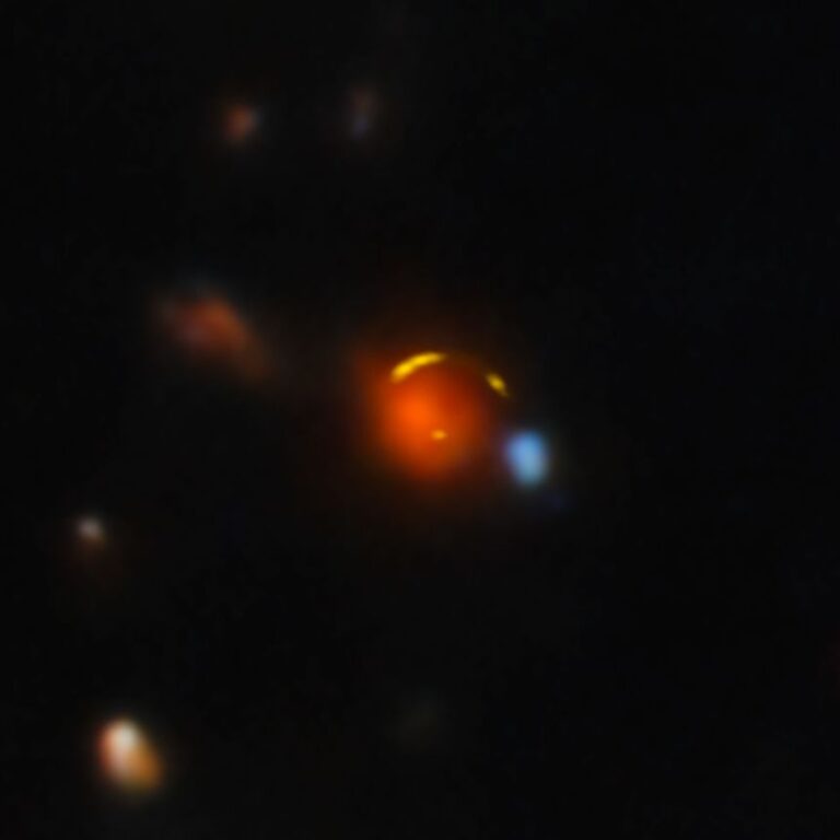 The red foreground galaxy bends the light of the more distant Shadow Blaster galaxy.