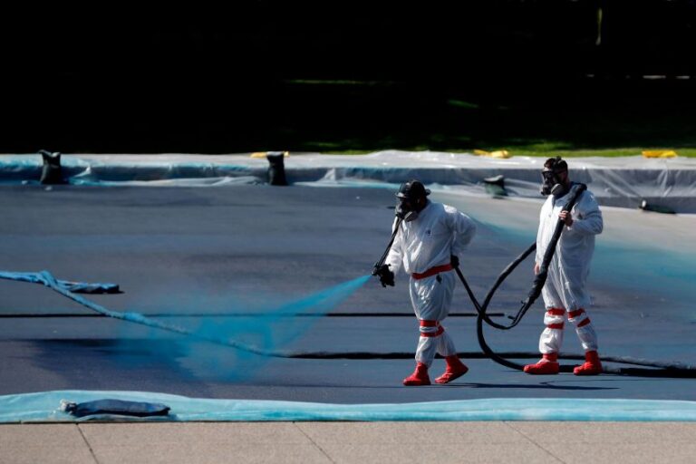 Workers apply a blue protective coating in May.