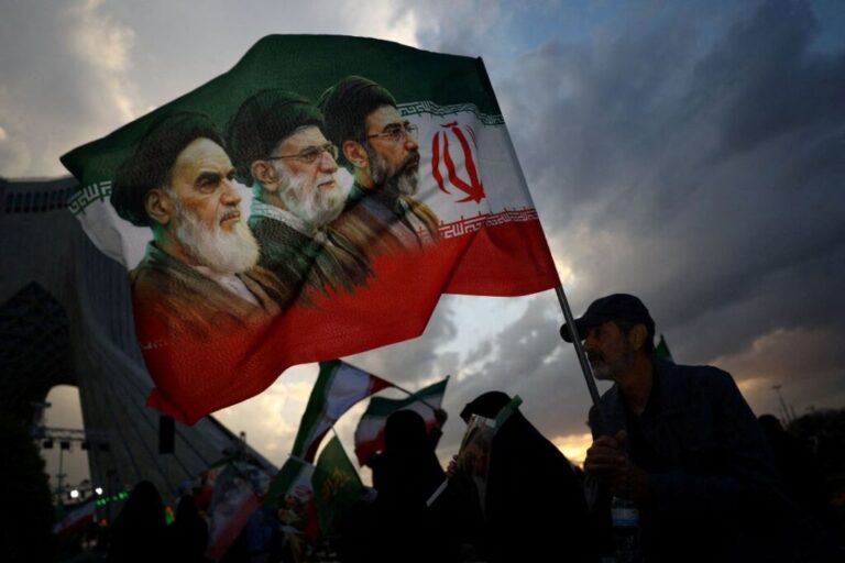 A man holds a flag with a picture of Iran's former and current leaders during a rally in Tehran on April 29, 2026.