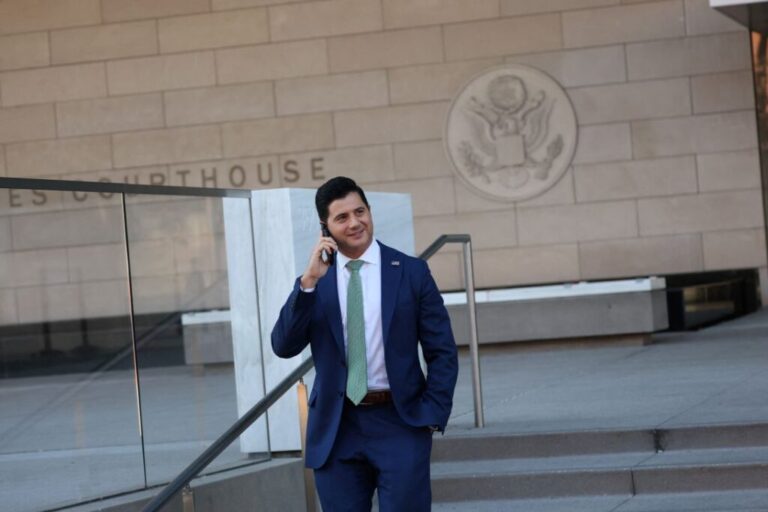 Bill Essayli speaks on the phone outside the United States District Court in Los Angeles, California, on December 16, 2025.