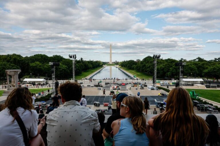 People sit on the steps of the Lincoln Memorial as construction continues on a stage for a UFC Freedom 250 press conference and the Lincoln Memorial Reflecting Pool is refilled with water, after being painted blue at the direction of U.S. President Donald Trump for the 250th anniversary of U.S. Independence, in Washington, DC on June 8.