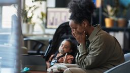 Child with her mother in modern office space, child playing with toy as mother focuses on her. Scene shows bond between family members within workspace