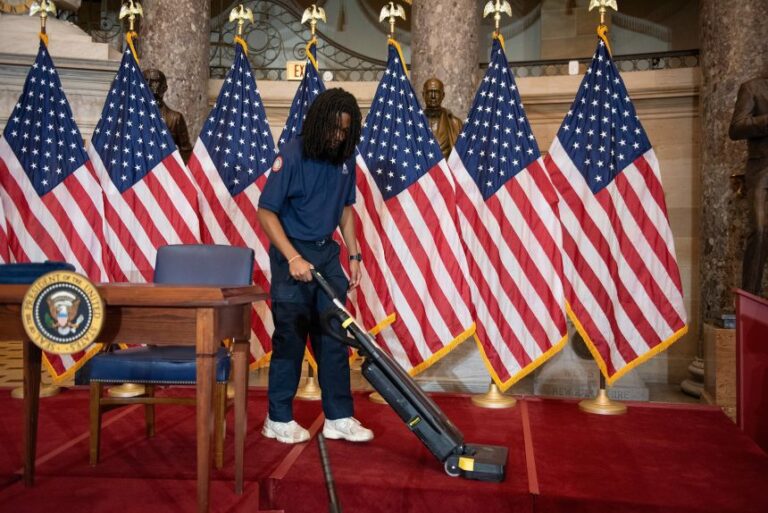 A worker vacuums the stage where President Donald Trump was meant to sign a housing affordability bill, in the US Capitol on Wednesday.