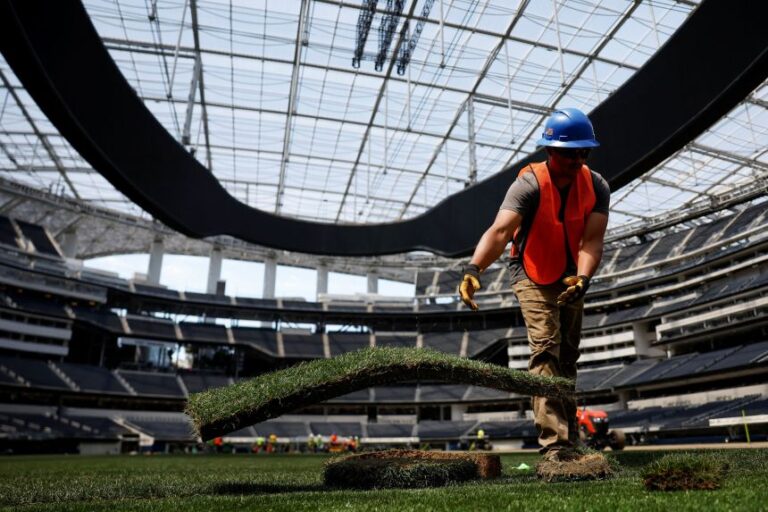 A worker installs a patch of grass to be used as part of the pitch at SoFi Stadium, ahead of the FIFA World Cup soccer tournament, in Inglewood, California, on May 13.