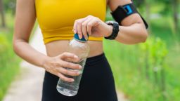 A woman holds a water bottle to drink water after working out.
