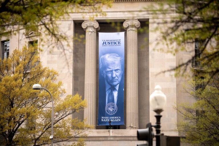 A large image of US President Donald Trump hangs from the Justice Department on April 3, in Washington, DC.