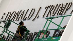 A worker stands on a lift, under President Donald Trump's name at the facade of the John F. Kennedy Center for the Performing Arts in Washington, DC, a day after its board announced it would rename the institution The Donald J. Trump and The John F. Kennedy Memorial Center for the Performing Arts, on December 19, 2025.
