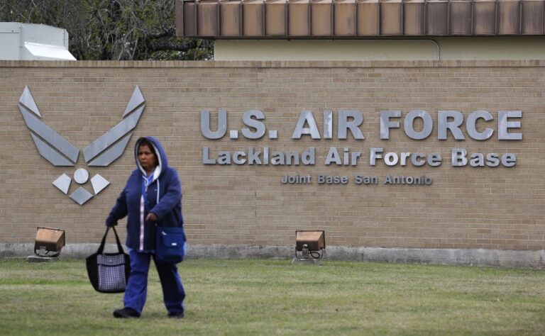 A pedestrian passes the main gate at Lackland Air Force Base in San Antonio, February 5, 2020.