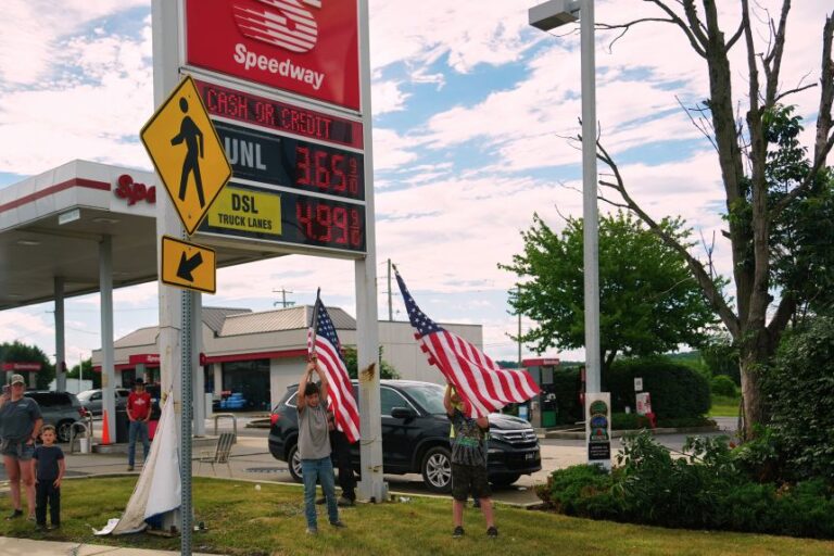 People hold flags in front of a gas station as President Donald Trump's motorcade passes by, in Pennsylvania, on Tuesday.