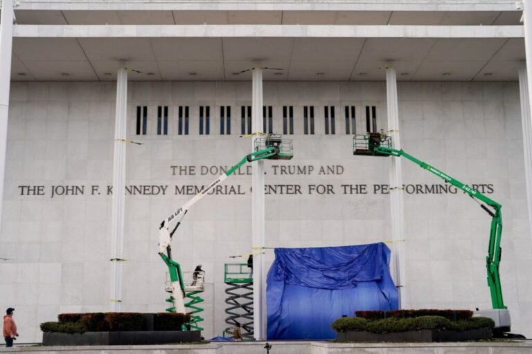 Workers affix signage adding President Donald Trump's name on the facade of the Kennedy Center in Washington, DC, on December 19, 2025.
