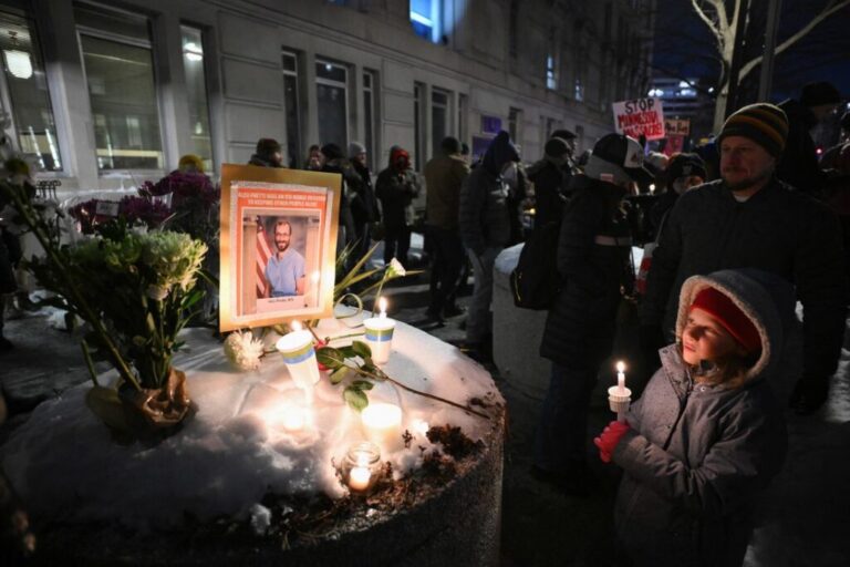 A child holds a candle next to a makeshift memorial for Alex Pretti, outside of the US Department of Veteran Affairs in Washington, DC, on January 28.