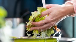 Female hands holding lettuce under the tap water