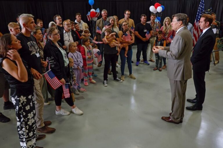 South Africans listen to US Deputy Secretary of State Christopher Landau and Homeland Security Deputy Secretary Troy Edgar as they deliver welcome statements in a hangar at Atlantic Aviation Dulles near Washington Dulles International Airport on May 12, 2025.