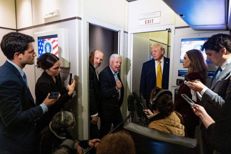 Sen. Lindsey Graham stands with President Donald Trump and Commerce Secretary Howard Lutnick, as they speak with reporters while in flight on Air Force One, on January 4.