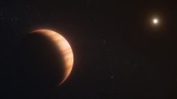 Exoplanet WD 1856 b, shown in this artist’s concept, is a gas giant that survived the death of its star. It now orbits a white dwarf at a distance 50 times closer than Earth orbits the Sun. Observations by the NASA/ESA/CSA James Webb Space Telescope not only determined the planet’s temperature but also detected molecules in its atmosphere. The former measurement provides evidence that WD 1856 b migrated to its current location billions of years after its star became a white dwarf. [Image description: An orange gas giant planet at left, taking up about one-third of the frame, facing a star, which appears at top right as a far smaller bright dot. The planet has subtle orange cloud bands. The star illuminates the right side of the planet like the crescent of a waxing moon. Both are on the black background of space. The words “artist’s concept” are in the bottom right corner.]