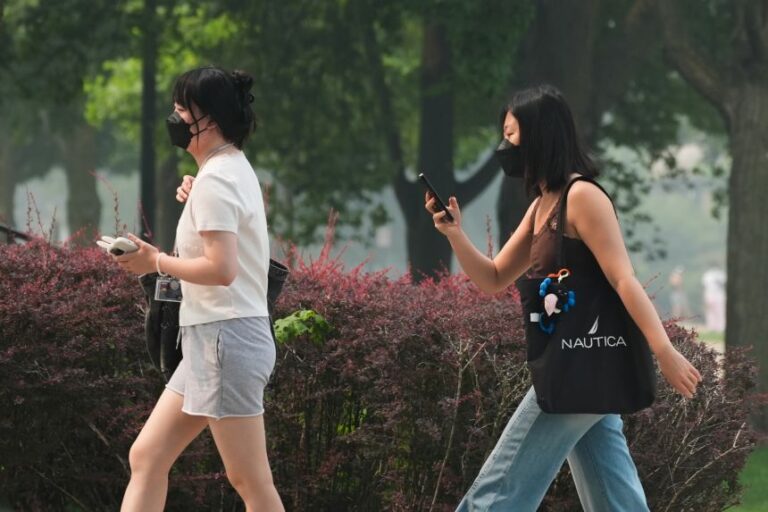 Pedestrians wear masks due to dense smoke from Canadian wildfires in Evanston, Illinois, on Thursday, July 16.