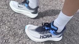 A person wearing Hoka Rocket X 3 running shoes on cement.
