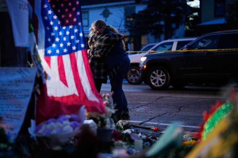 People hug in Minneapolis while visiting a makeshift memorial for Renee Good on January 12. Good, a 37-year-old US citizen, <a href=