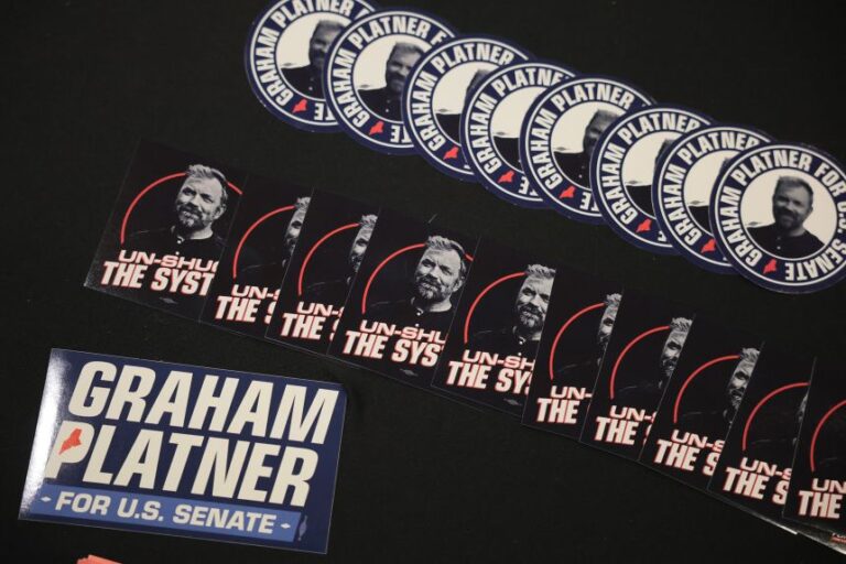 Campaign stickers for Graham Platner sit on a table during a “Fighting Oligarchy” tour stop held by Sen. Bernie Sanders on the University of Maine campus in Orono, Maine, on May 24.