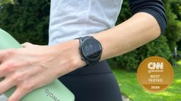 Woman holding water bottle wearing a running watch.