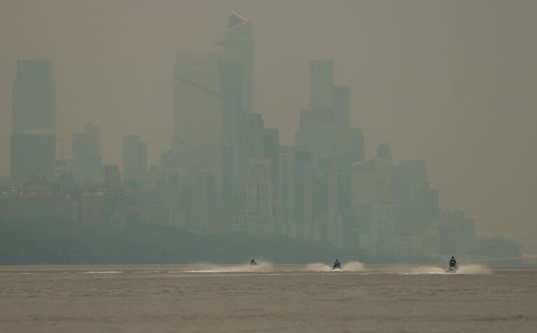 People ride personal watercraft on the Hudson River toward Manhattan through a cover of wildfire smoke on July 16.