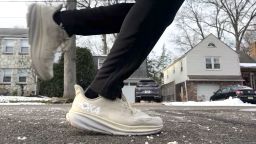 The lower legs and feet of someone running on the street.