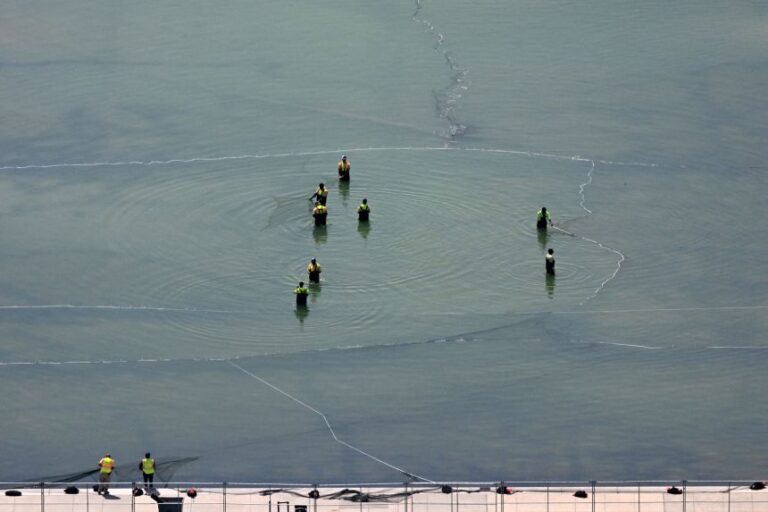 People work in the Lincoln Memorial reflecting pool as seen from the Washington Monument in Washington, DC, on June 30.