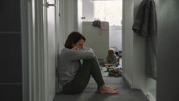 mother sitting on landing floor whilst her baby plays in the background
