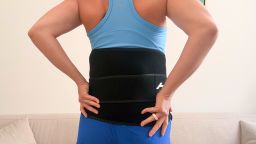 Woman wearing black lower back brace with hands on hips
