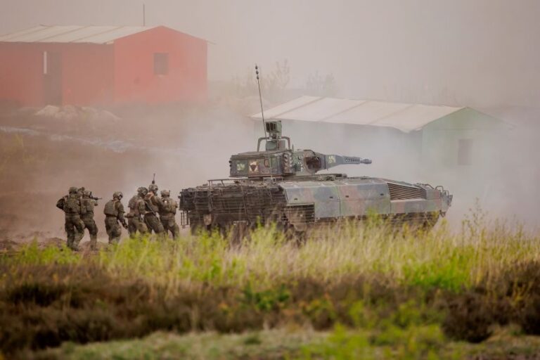 Soldiers walk behind a tank near Munster, Germany, as part of a demonstration of capabilities by the German army on May 4.