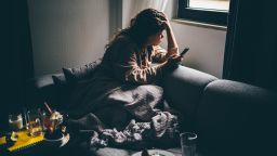 Sad and depressed woman using smartphone at home.