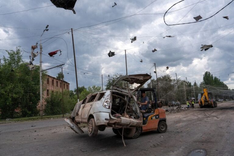 Communal workers clean a road at a site of a Russian air strike in the frontline city of Sloviansk, Ukraine, on July 24.