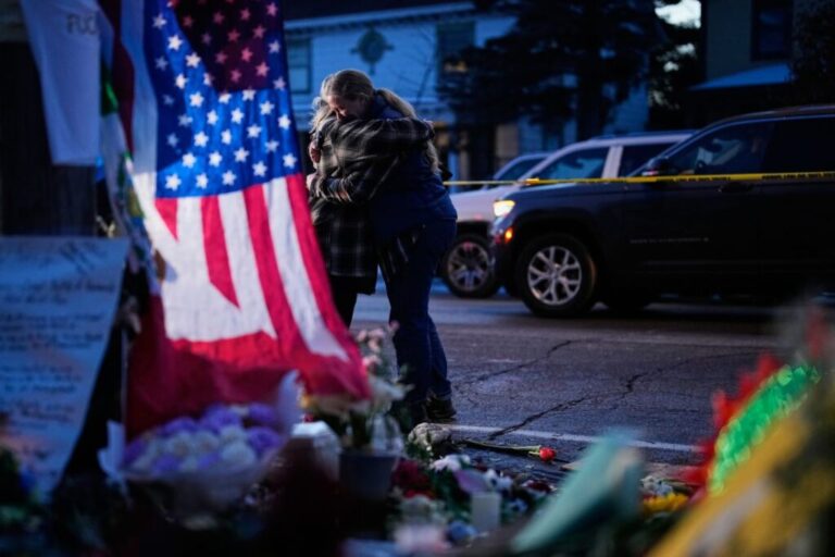 People share an embrace while visiting a makeshift memorial for Renee Good, in Minneapolis, on January 12.