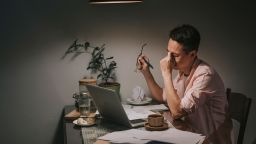 Asian chinese male working late at home dining room emotional stress with his financial bill alone at night